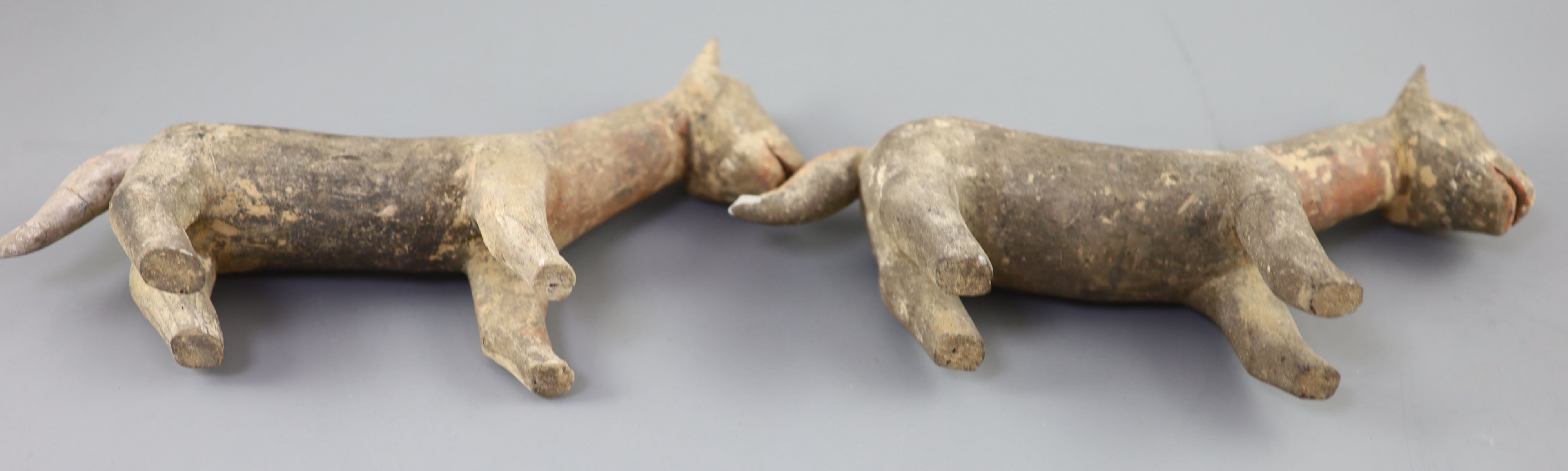 A pair of Chinese grey pottery models of dogs, Han dynasty or later, 26cm long, repairs